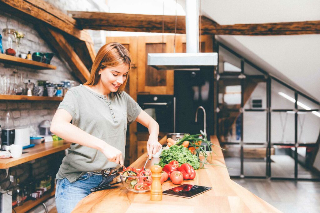 Frau kocht gesunde Mahlzeit in ihrer Küche.